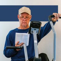 older man on stationary bicycle reading